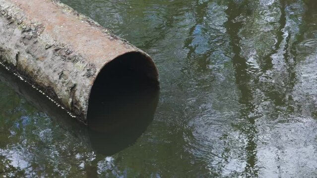 Old rusty sewer pipe for discharging waste into pond.