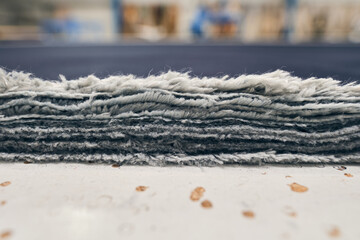 A pile of raw denim sheets fresh off a production line in a denim factory. Industrial fabric and fashion manufacture. Stylish blue denim fabric for wholesale and jeans.
