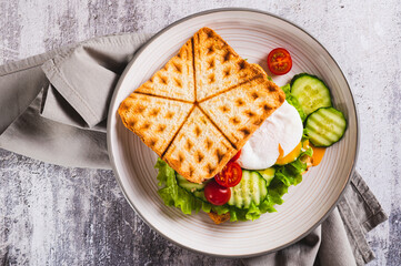 Close up of waffle bread sandwich with poached egg and vegetables on a plate  top view