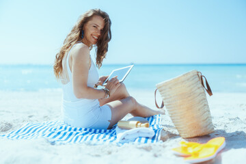 happy stylish woman on ocean shore using applicationst PC