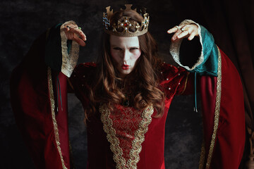 scary medieval queen in red dress with white makeup and crown