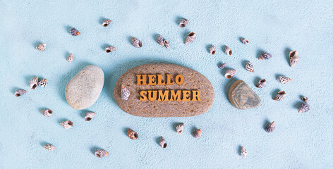 Concept hello summer text on stone surrounded by seashells on blue background top view web banner