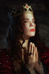 medieval queen in red dress with crown praying