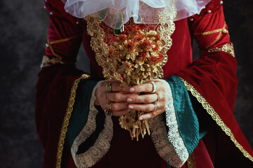 Closeup on medieval queen in red dress with dried flower
