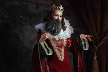 medieval queen in red dress with fan, white collar and crown