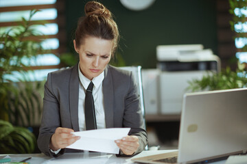 pensive modern female worker in modern green office