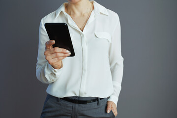 Elegant woman worker using smartphone against grey