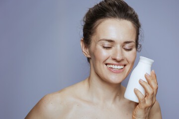 smiling modern woman with cosmetic cream jar on blue