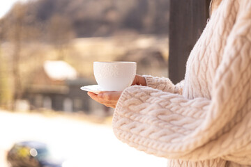 female hands in a sweater hold a cup of coffee