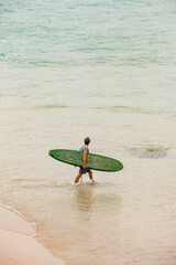 Surfer's Serenity: Man Walking with Green Surfboard by the Beach
