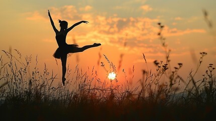   A silhouetted ballerina in a field of tall grass Sun sets in the distance