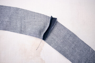 A pile of raw denim sheets being trimmed, fresh off a production line in a denim factory....