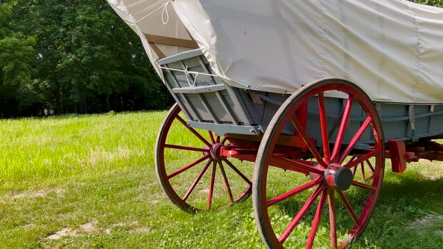 Restored 19th century style covered wagon or horse Drawn Carriage. Side views. Rural village scene.
