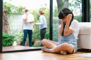 Stressed and unhappy young girl huddle in corner, cover her ears blocking sound of her parent...