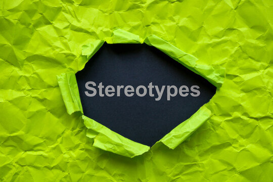 Torn crumpled paper and a word stereotypes on a dark surface.