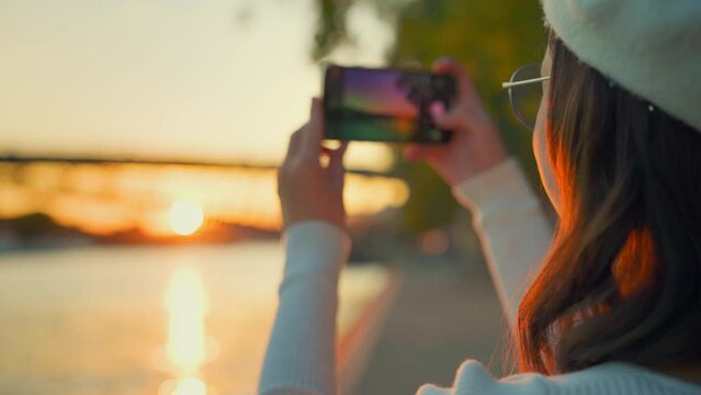 Person Capturing Sunset on Smartphone