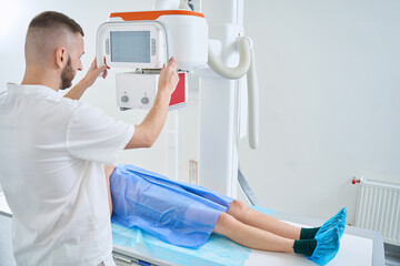 Radiologic technologist is preparing adult man for digital abdominal radiography