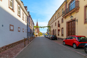 A picturesque street in the small town of Ammerschwihr, France, part of the Alsatian wine route of wine producing villages, with the Prankster Tower in view at the end of the street.