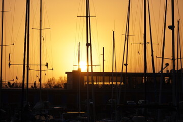 Beautiful orange sunset sky with silhouettes of boats moored in the harbor.