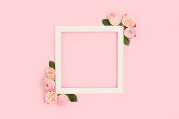 Square frame made of pose flowers and green leaves on a pink background. Place for your design.