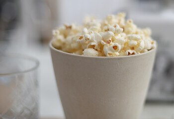 Off white ceramics cup filled with fresh popcorn. Very selective focus
