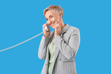 Mature woman talking by telephone on light blue background
