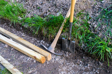 Spade shovel and pick ax with landscape timbers for digging a low landscape wall