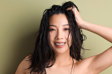 Young Asian woman with wet hair on green background, closeup