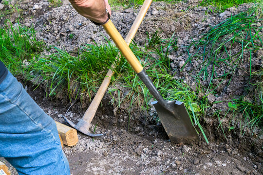 Man using a spade shovel to dig an  incline to level out for landscape wall