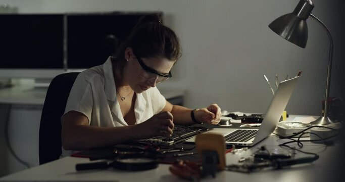 Tools, motherboard circuit and woman repair computer hardware, electronics or semiconductor system in dark lab workshop. IT equipment, engineering industry or female technician fixing laptop at night
