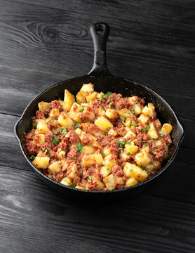 Corned beef hash with potatoes in iron cast pan