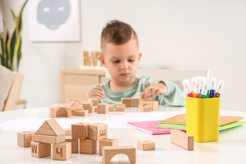 Felt-tip pens with wooden blocks and copybooks on table of little boy at home, closeup