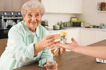 Senior woman taking pill bottle in kitchen