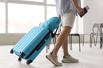 Male tourist with passport and bags walking at airport