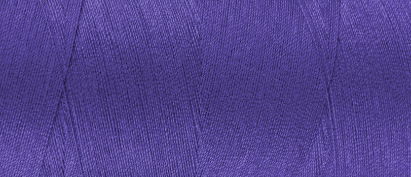 Texture of purple color threads in spool close up, macro. Wide banner, header of sewing threads bobbin abstract background, wallpaper, backdrop.