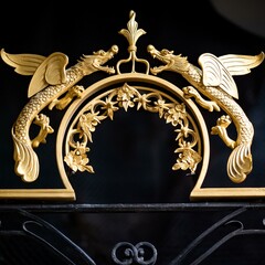 A golden decorative element of a luxury mansion gate featuring two roaring dragons facing eachother...