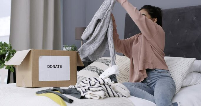 Woman, folding of clothes and donation for charity organization and giving with kindness in bedroom. Person, humanity and packing of clothing in box, spring cleaning and generosity to ngo for help