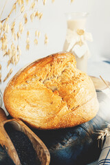 Round white bread. Close-up of white bread with homemade black salt in a wooden scoop on a light marble background. Close-up