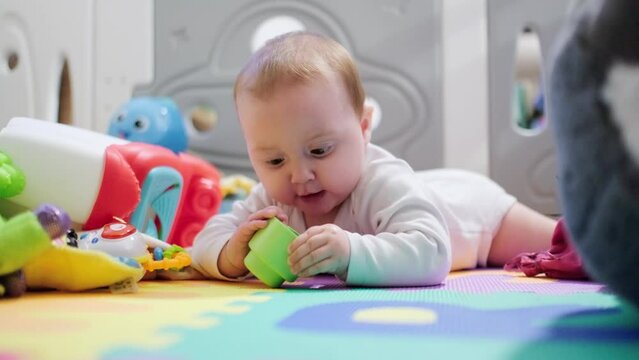 Baby exploring toys on colorful playmat at home