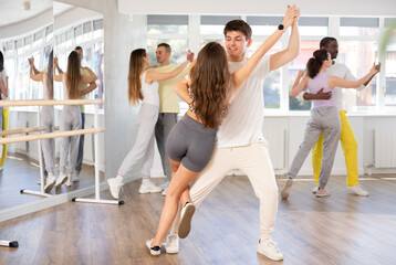 Pair of young woman and man enjoying of sensual tango dance in choreo class. Exciting hobby, active...