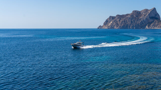 Luxury motor yacht. Boat navigating in front of Penyal d Ifach, Calpe, province of Alicante, Spain. Image for blog or travel guide. Penon de Ifac. High quality photo