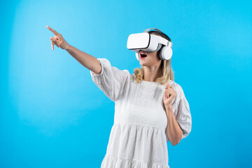 Caucasian girl in pajamas enter in metaverse while point at blue background. Excited woman in white...