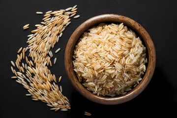 Brown rice in clay pot, uncooked and hulled, isolated on black.