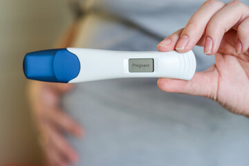 Close up of a pregnant woman holding a digital positive pregnancy test