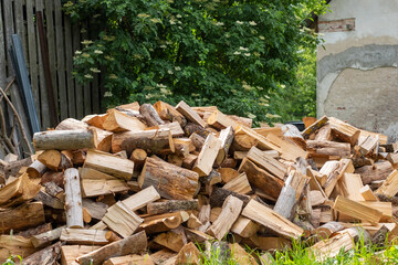 A large pile of freshly chopped firewood stacked in an outdoor rustic setting, ready for winter...