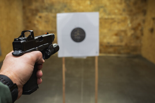Tactical pistol shooting at a target in a shooting range, first-person photo.