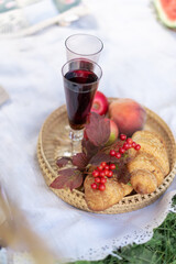 Still life with a glass of red wine on a picnic with croissants and fruits