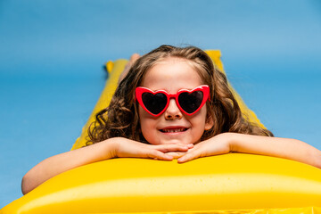 Happy child, red swimsuit, resting on inflatable mattress for swimming, hotel pool. Summer...