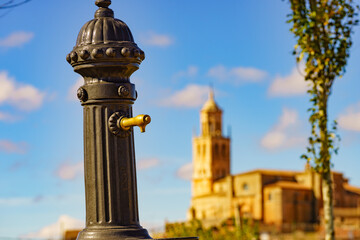 Fototapeta na wymiar Old hydrant and church in town Santa Maria del Campo, Spain.