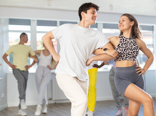 Slim young man and woman practicing national dance in training hall during group dancing classes